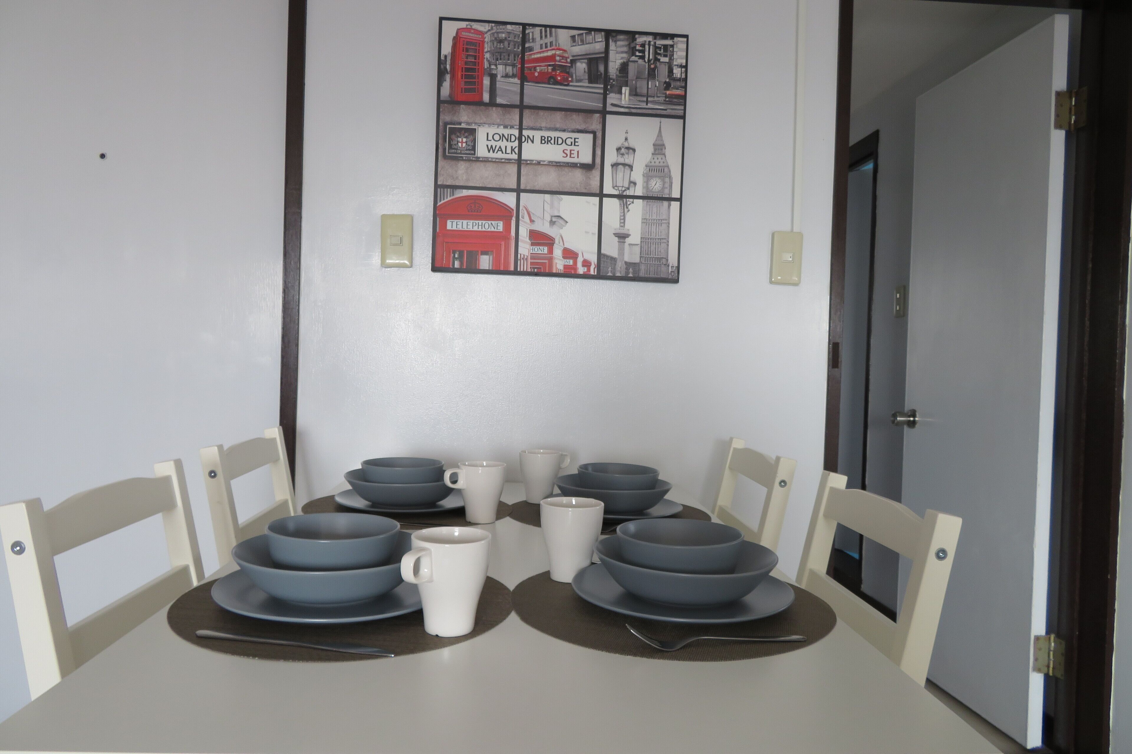 Une table à manger avec quatre bols gris et deux tasses blanches, posés sur une nappe blanche.