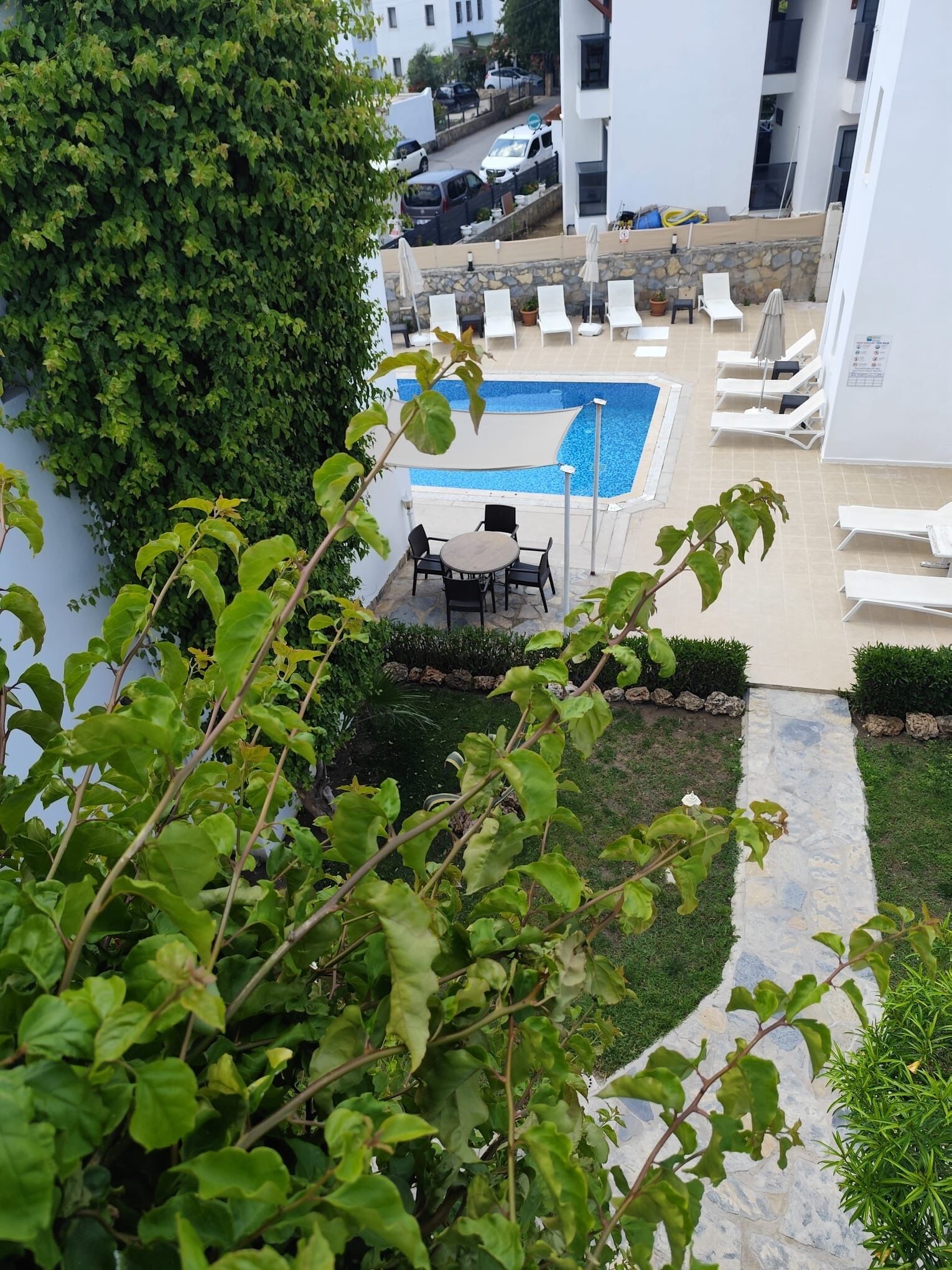 A rooftop pool area with lounge chairs, a table, and a stone pathway.