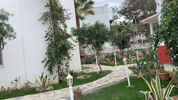 A garden pathway leading to a white building with a stone-tiled entrance.