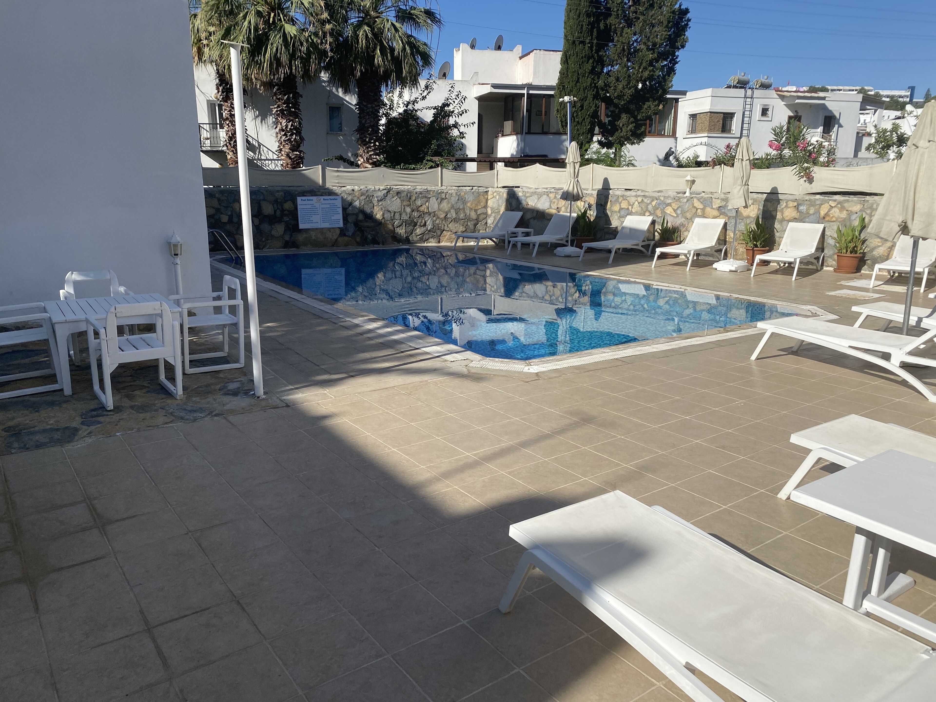 A pool area with lounge chairs and a stone wall.