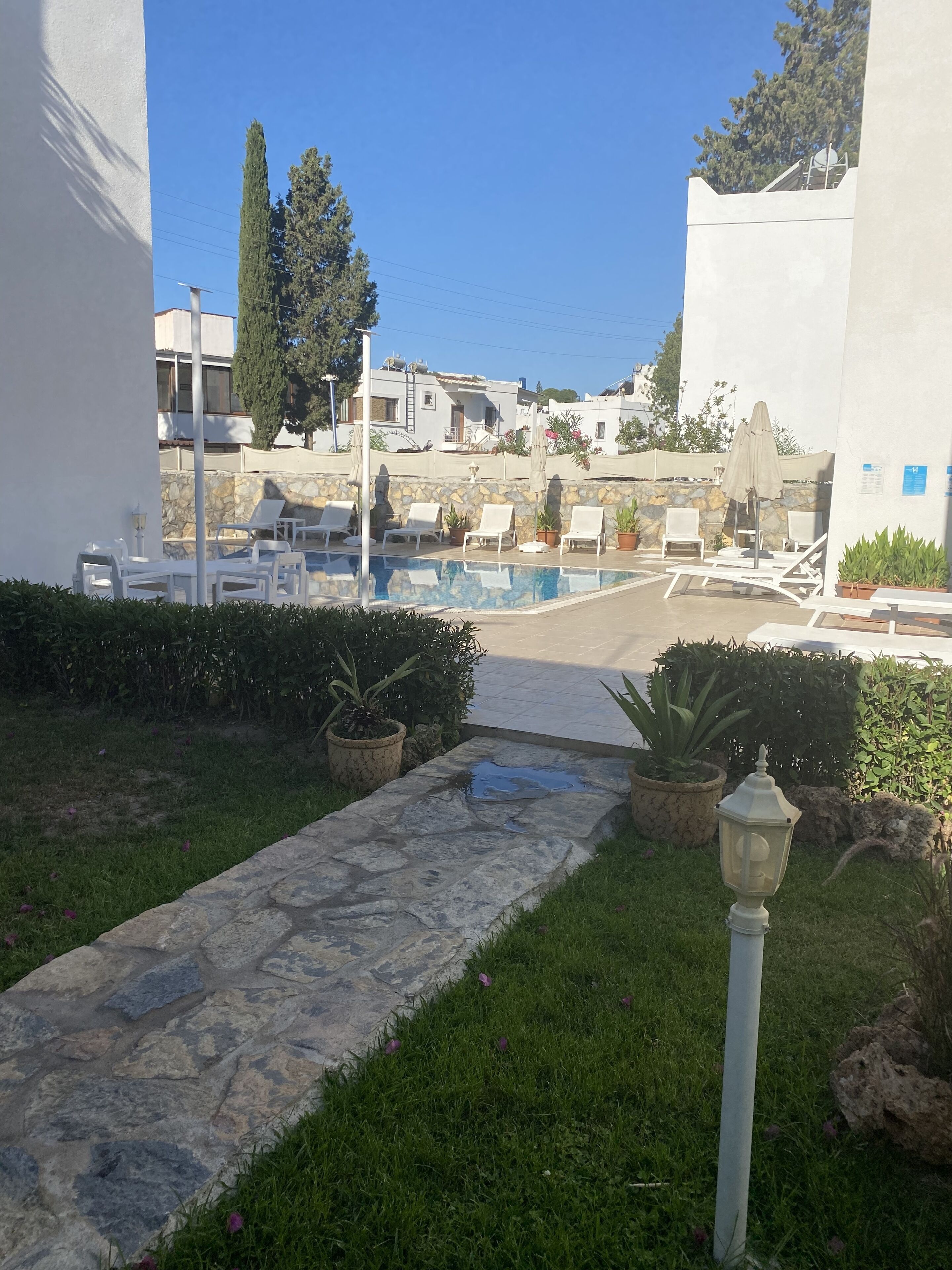A pool area with lounge chairs and a stone pathway leading to the water.