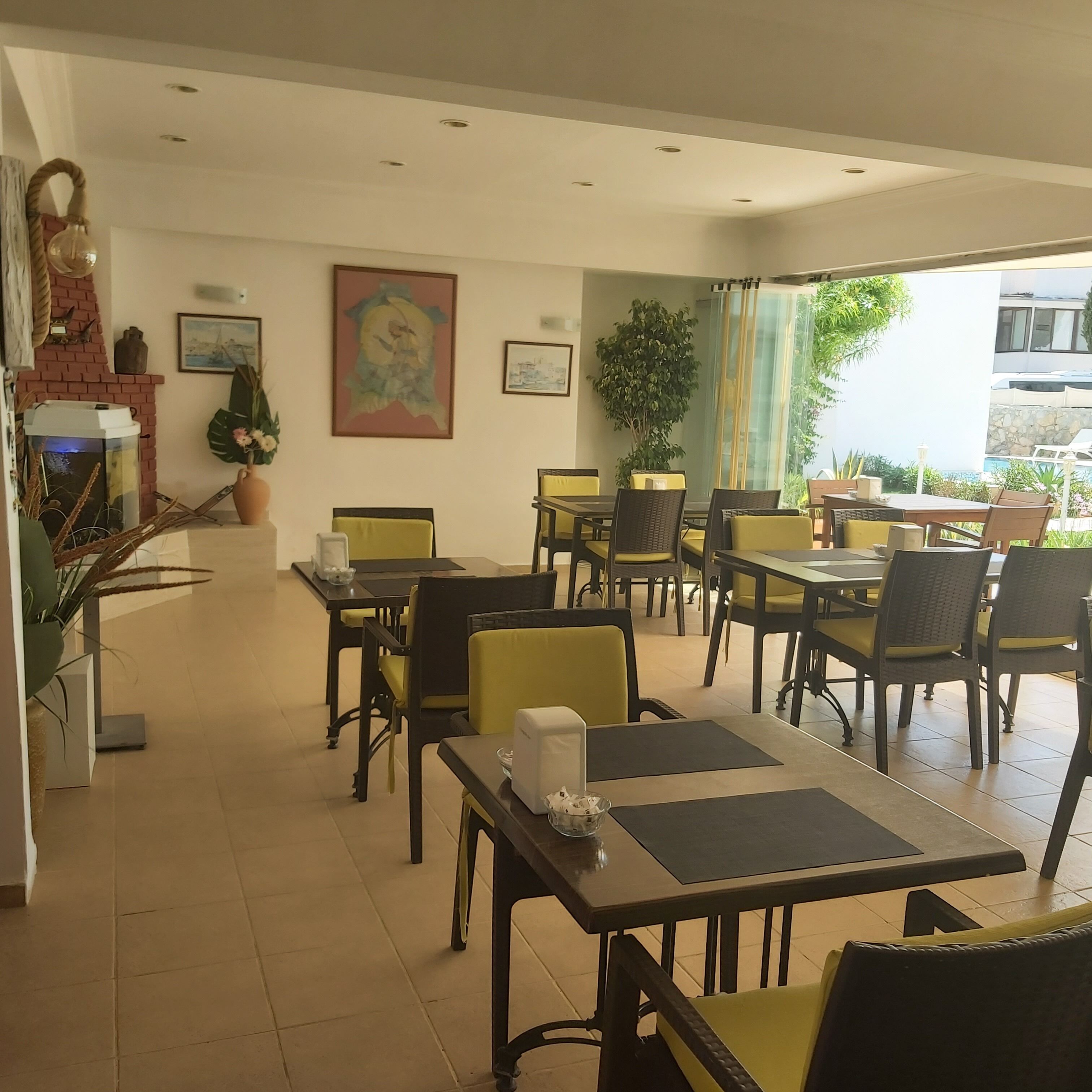 Un restaurante con mesas dentro, chimenea y vistas al exterior.