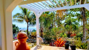 A covered patio with a view of a tropical garden and the ocean. - Ocean Views, Private Pool, and Lush Botanical Garden  (Governor's Harbour)