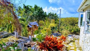 A garden with a small wooden structure, a stone pathway, and various tropical plants. - Ocean Views, Private Pool, and Lush Botanical Garden  (Governor's Harbour)