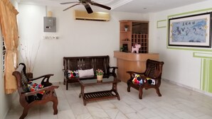 A living room with a ceiling fan, wooden furniture, a small table, and a wall-mounted shelf with decorative items. - StayWonderful01 Kota Laksamana (Malacca City)