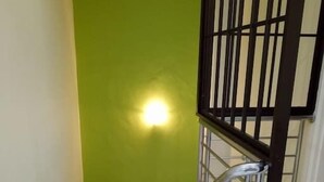 A staircase with a green wall and a light fixture on the wall. - StayWonderful01 Kota Laksamana (Malacca City)