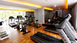 Un gimnasio con cintas de correr, elípticas y un espejo grande.
