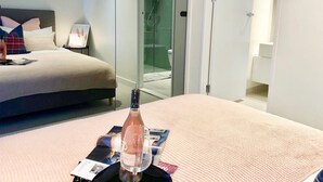 A hotel room with a bed, a glass shower enclosure, and a bottle of water on the bed. - Deluxe and Brand New Lakeside Apartment (Melbourne)