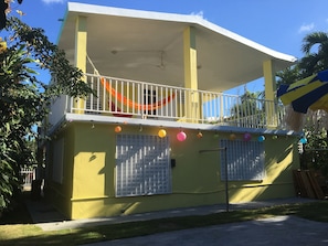 Stunning two-story building with a balcony featuring a charming lantern-adorned facade and a palm tree in the background.