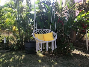 Relax in a serene outdoor setting surrounded by lush greenery and tropical plants.