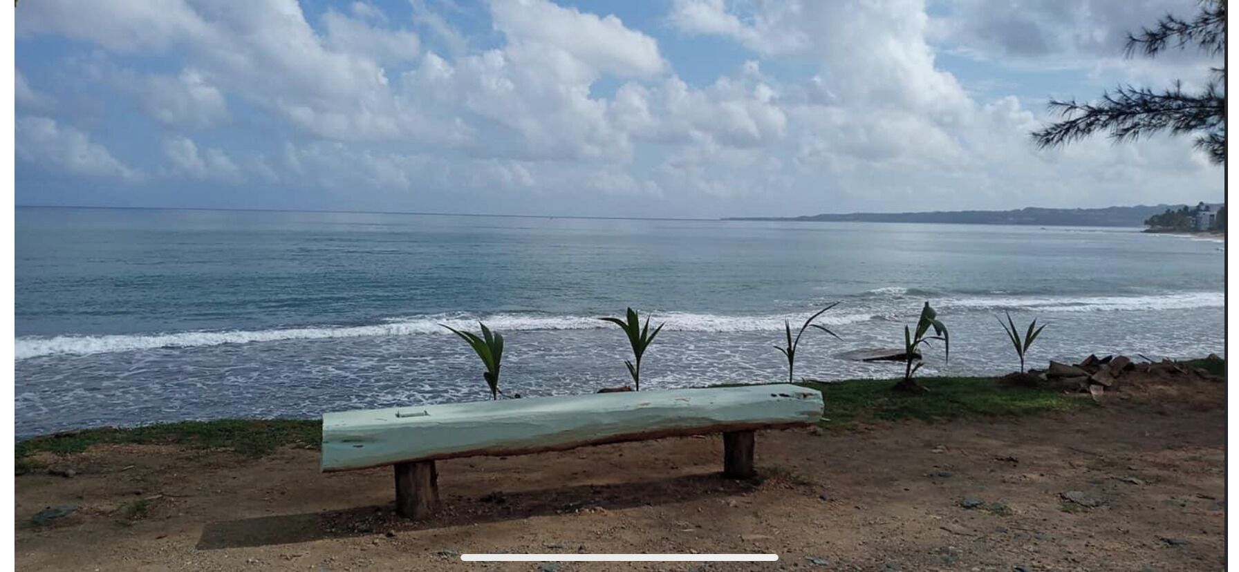 A bench by the sea with a view of the ocean and distant land.