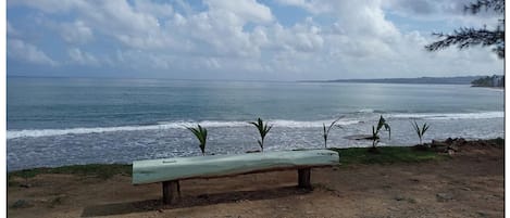 A bench by the sea with a view of the ocean and distant land.