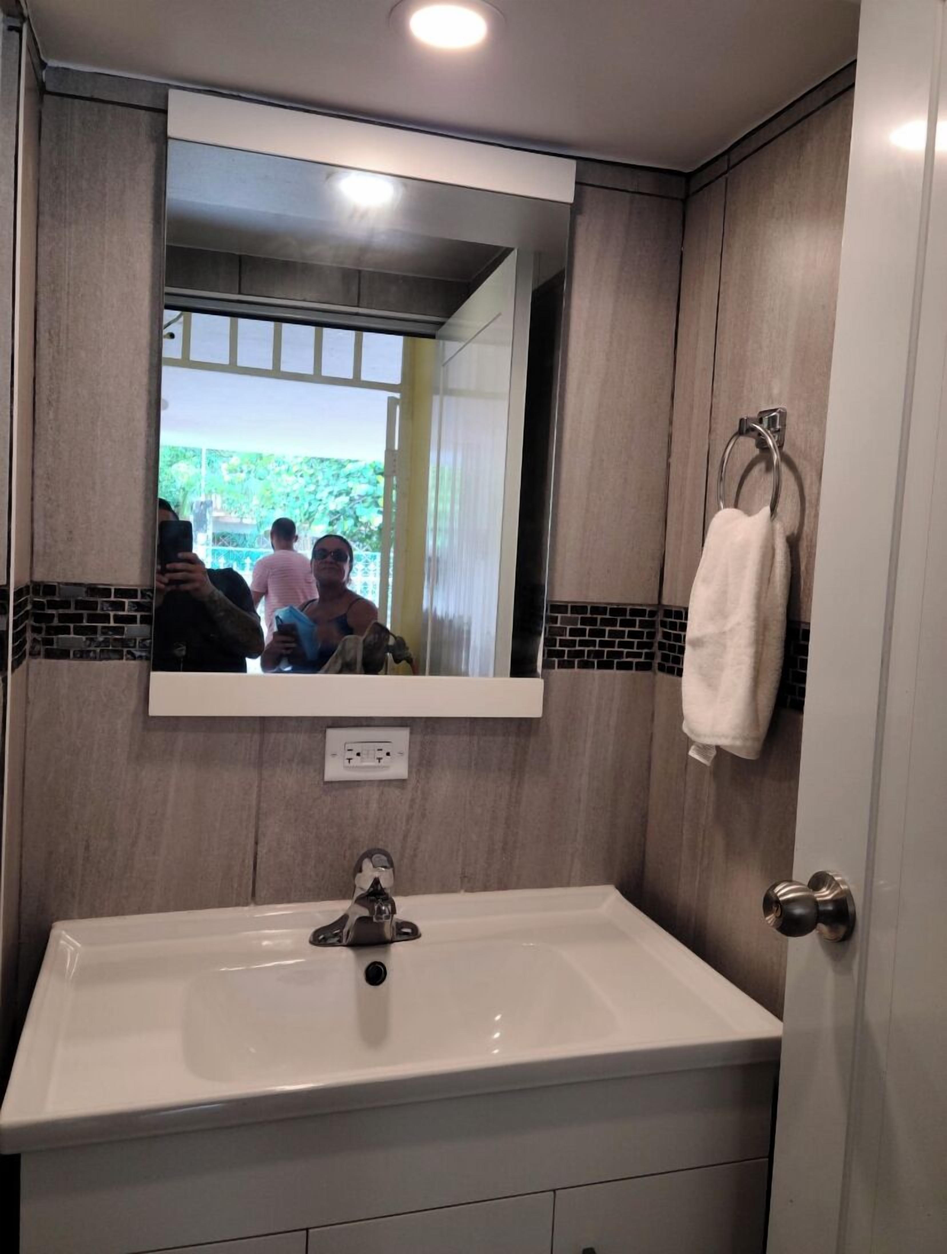 A bathroom with a white sink, a mirror, and a towel rack.