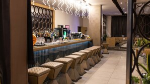 Eine Bar mit einer langen Theke, mehreren Hockern und einer dekorativen Leuchte.