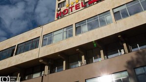 Ein Hotelgebäude mit einem auffälligen roten Schild, auf dem "HOTEL BPS" steht, und einem Logo mit drei Sternen.
