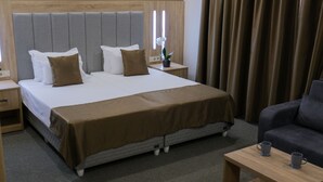 Ein Hotelzimmer mit einem großen Bett, einem Nachttisch mit Lampe, einem kleinen Tisch mit zwei Tassen und einem Sofa.