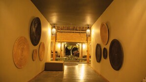 A hallway with a wooden floor, a central seating area, and a ceiling with hanging lights. - Wirdana Resort & Spa (Boossa)