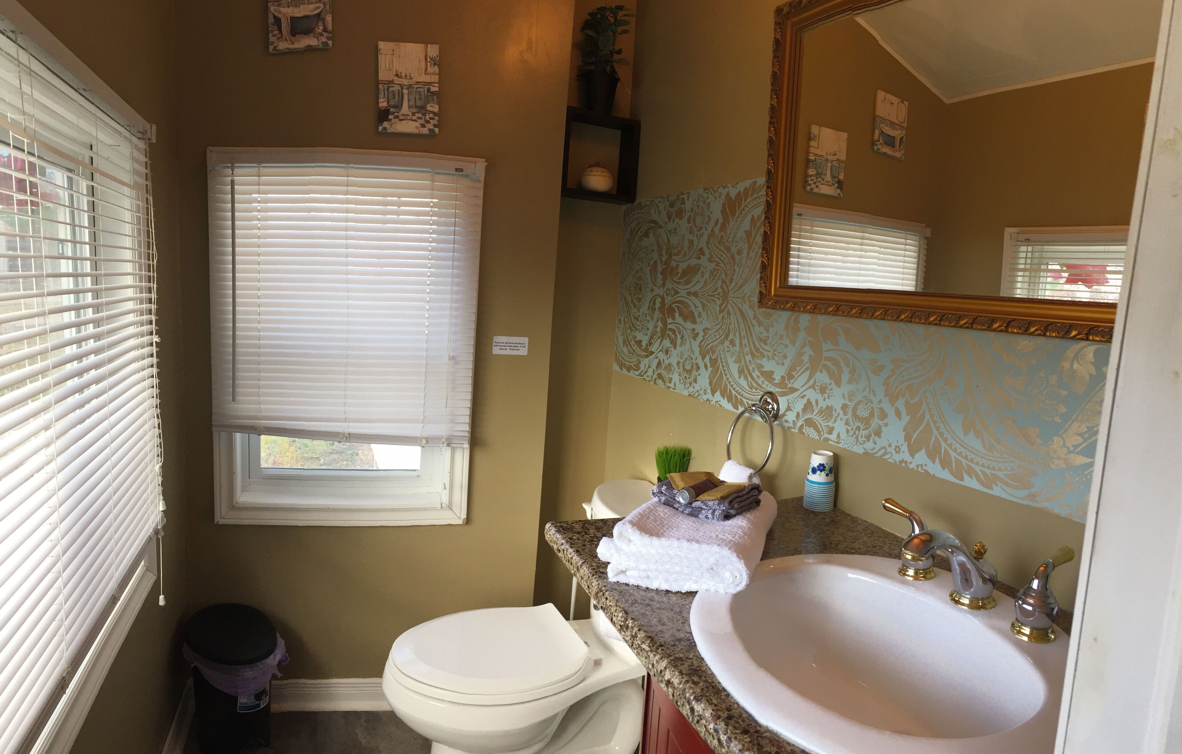 A bathroom with a toilet, sink, and window blinds.