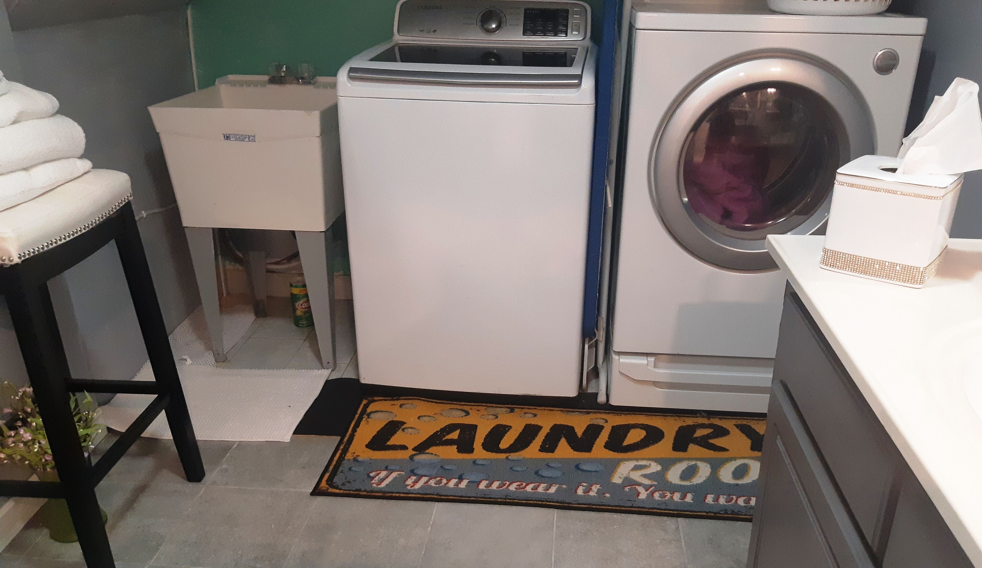 Un lavadero con lavadora, secadora y un felpudo que dice "LAUNDRY ROOM".