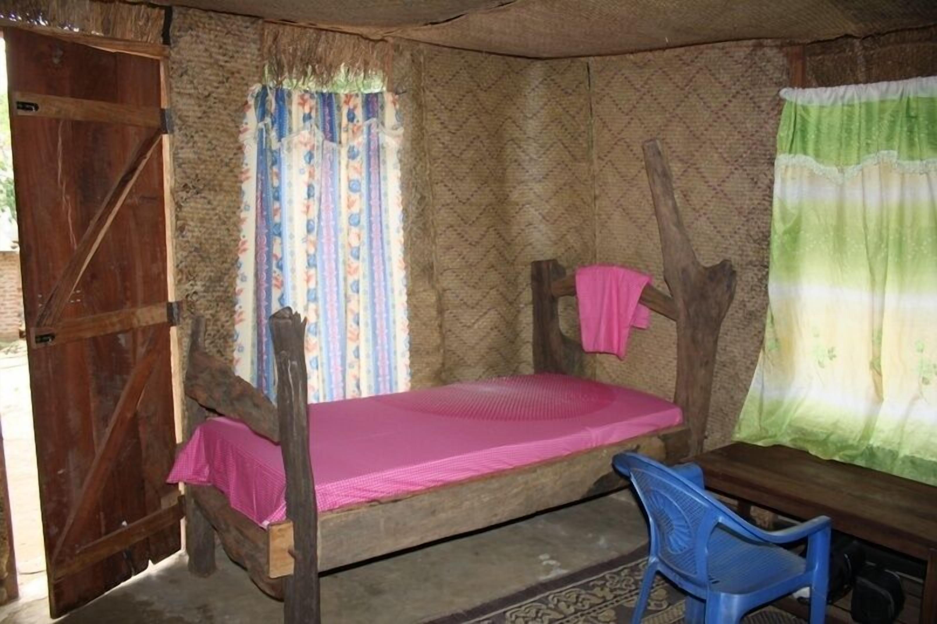 Une chambre rustique avec un lit superposé en bois, une petite table et une chaise en plastique bleue.