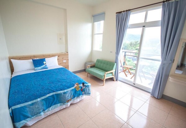 Un dormitorio con cama, una silla verde, una ventana con cortinas y un balcón.