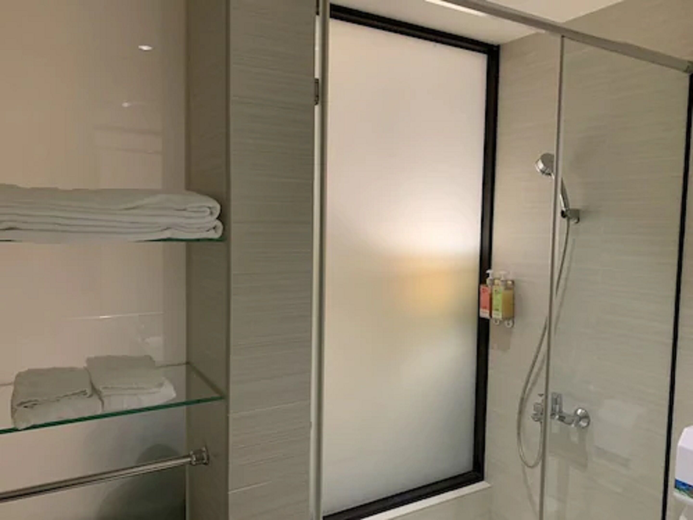 Une salle de bain moderne avec une douche à parois de verre, un porte-serviettes et une étagère en verre.