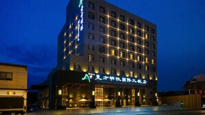 A multi-story hotel with illuminated signage and a well-lit entrance. - Ali Mountain Oriental Pearl International Hotel (Zhongpu)