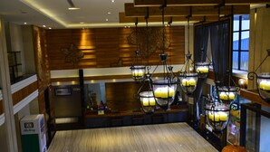 A hotel lobby with a marble reception desk, wooden panel walls, and multiple chandeliers with candles. - Ali Mountain Oriental Pearl International Hotel (Zhongpu)