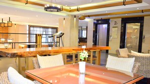 A modern hotel lobby with a glass-top table, wicker chairs, a treadmill, and a reception desk. - Ali Mountain Oriental Pearl International Hotel (Zhongpu)