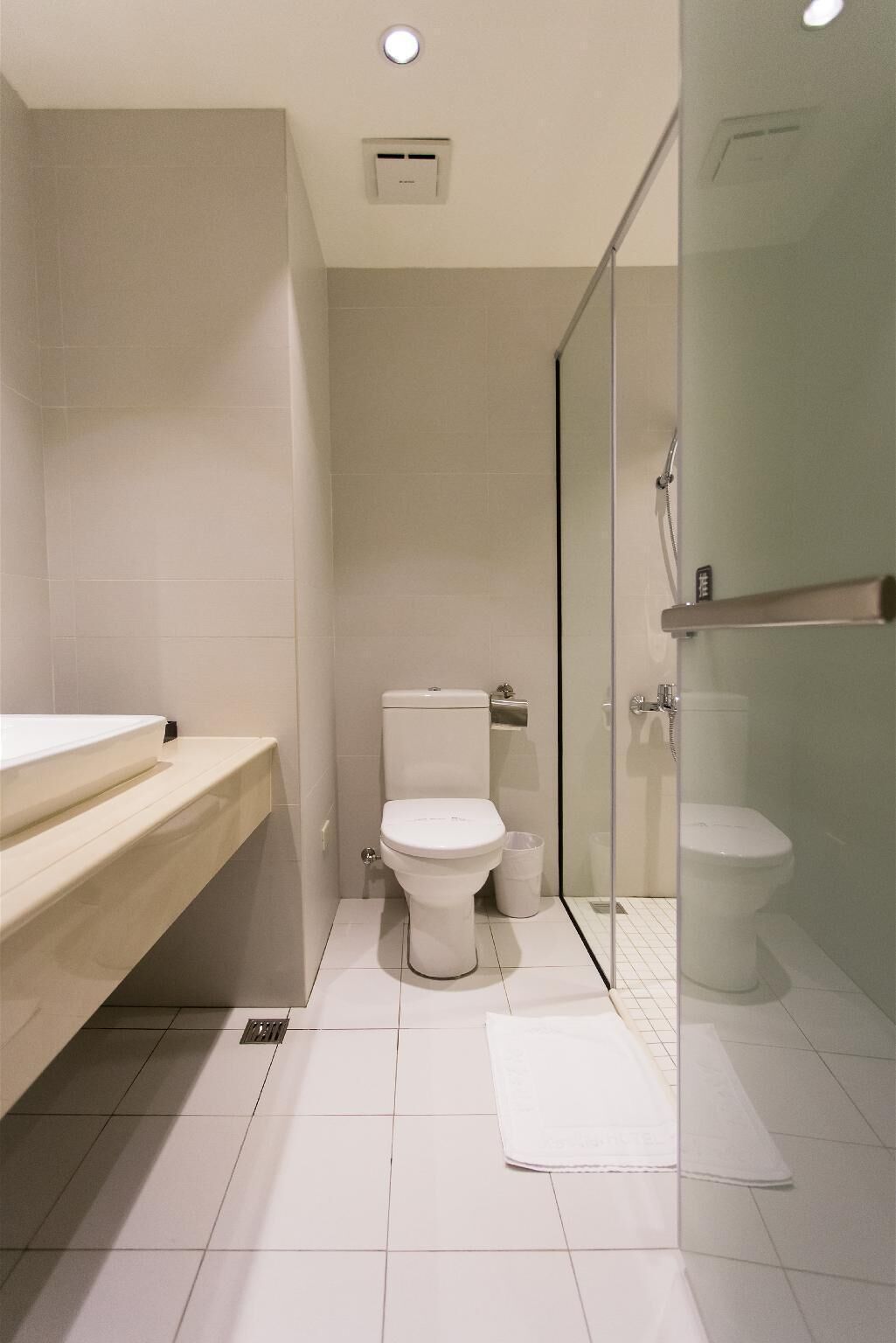 A modern bathroom with a toilet, sink, and glass shower enclosure.