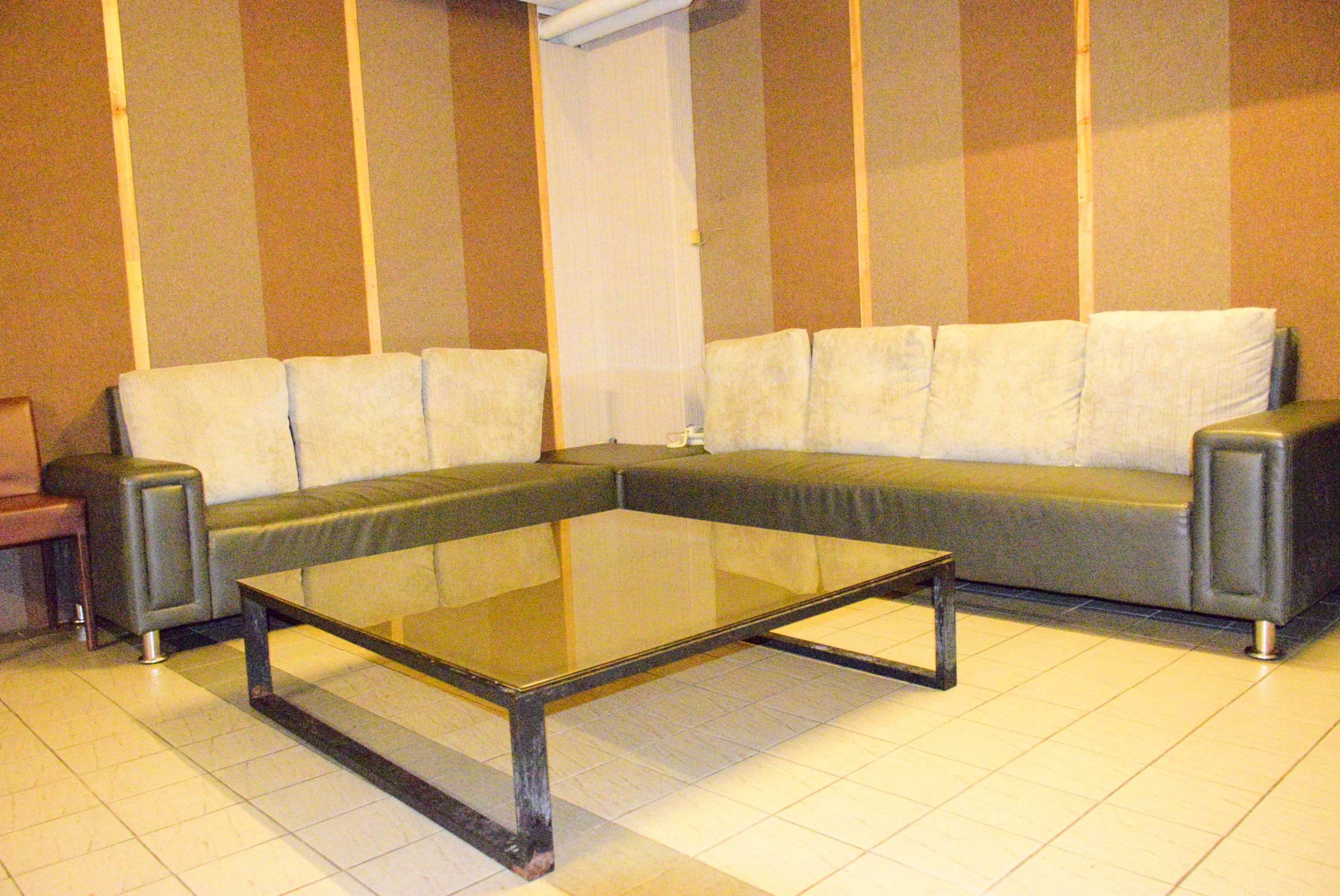 Una sala de estar con un sofá seccional, una mesa de centro de vidrio y una mesita auxiliar.