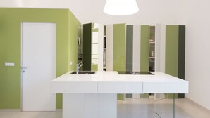 Una cocina moderna con encimera blanca, paredes de acento verde y un armario de vidrio.