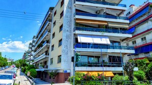 A multi-story building with balconies, a visible street, and parked cars. - Groovy Apartment by the Sea with Garden (Alimos)