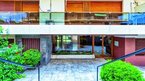 A modern building with a glass balcony, a brick facade, and a tiled ground. - Groovy Apartment by the Sea with Garden (Alimos)