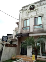 A building with a stone facade, two balconies with metal railings, a sign with Japanese characters, and a wet floor sign.