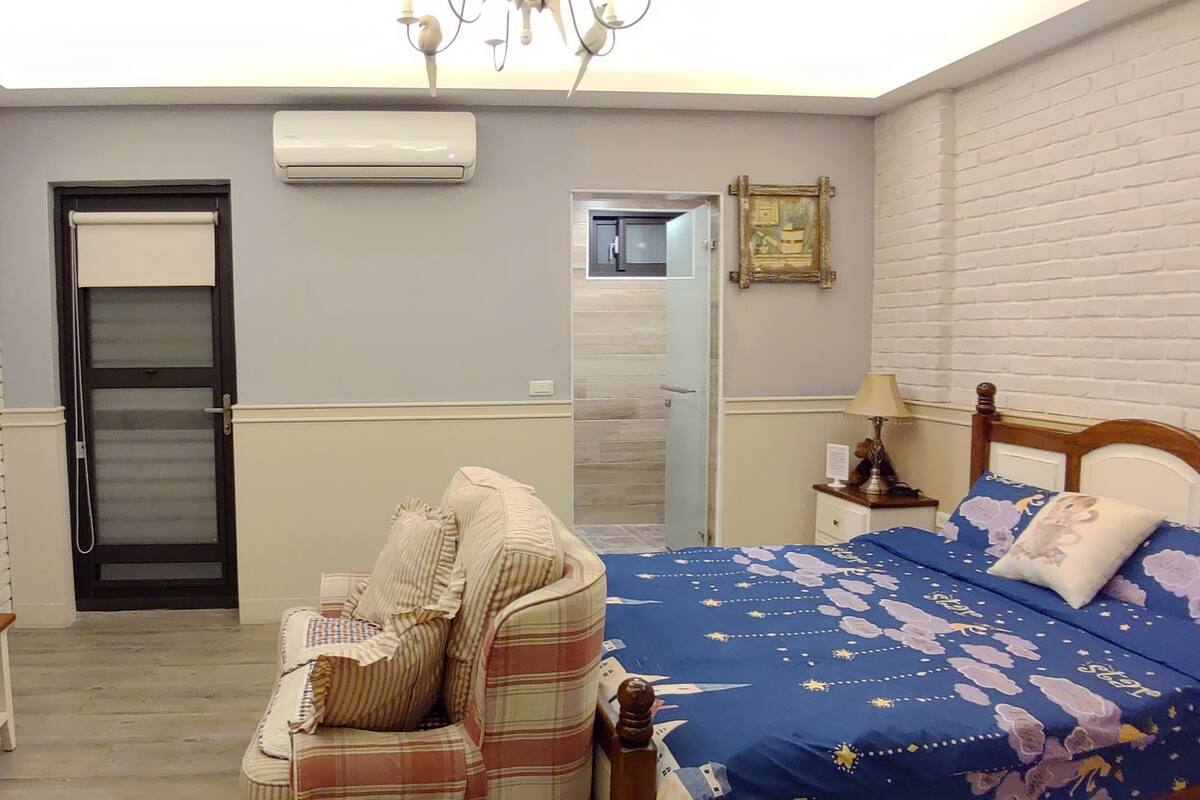 Quarto com cama, televisão, escrivaninha e porta.