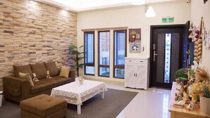 Un espace d’accueil avec un mur en pierre, un canapé marron, une table blanche et un meuble contenant des objets décoratifs.
