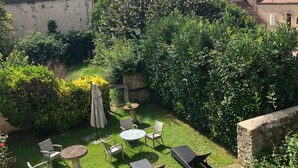 Een verzorgde tuin met een zitgedeelte, omgeven door weelderige begroeiing en een stenen muur.