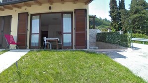 A house with a covered patio, a lawn, and a red chair.