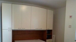 A bedroom with a bed, a wardrobe, and a small shelf unit.