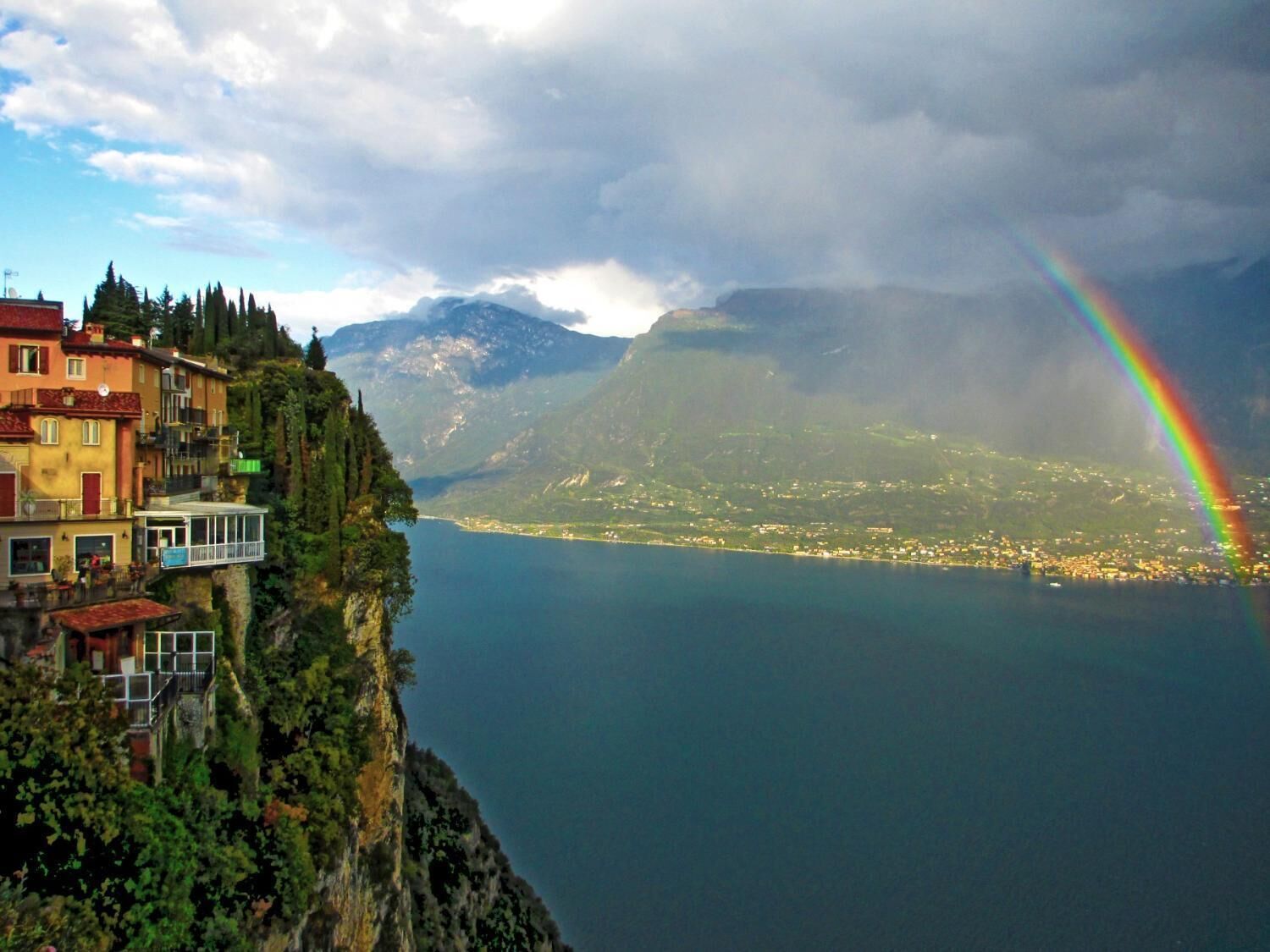A coastal town with a mountain backdrop and a rainbow.