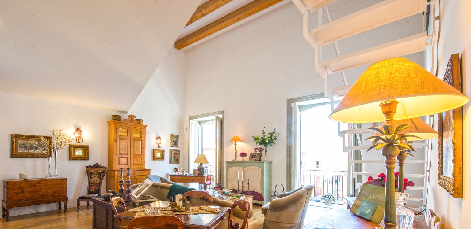 A spacious living room with a dining area, wooden furniture, and a large window providing natural light.