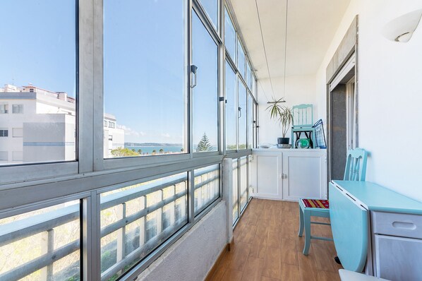 A balcony with large windows, a wooden floor, and a blue chair.