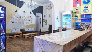 A modern interior with a long counter, seating area with sofas, and a wall decorated with colorful artwork. - Moosica Hostel (Tbilisi)