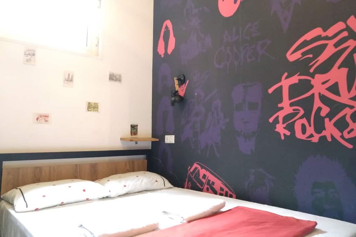 A bedroom with a bed, a shelf with pictures, and a wall with graffiti.