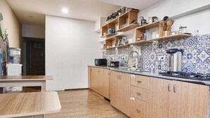 A kitchen with wooden cabinets, a countertop, and a backsplash with a blue and white pattern. - Moosica Hostel (Tbilisi)
