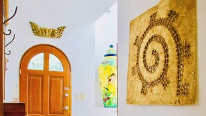 Ein Flur mit einer Holztür, einer Treppe und einem an der Wand befestigten Kunstwerk.