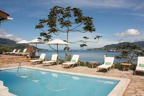 Relax by the pool with a view of the distant mountains and a large body of water.