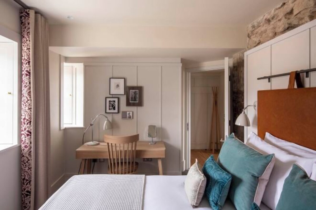 A bedroom with a bed, pillows, a desk, and a chair.