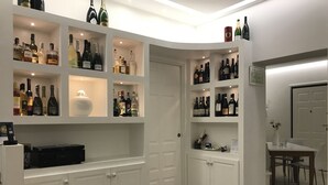 A well-lit wine cellar with multiple shelves of wine bottles, a small table with a vase, and a door leading to another room. - SunWine Bed & Breakfast (Taranto)